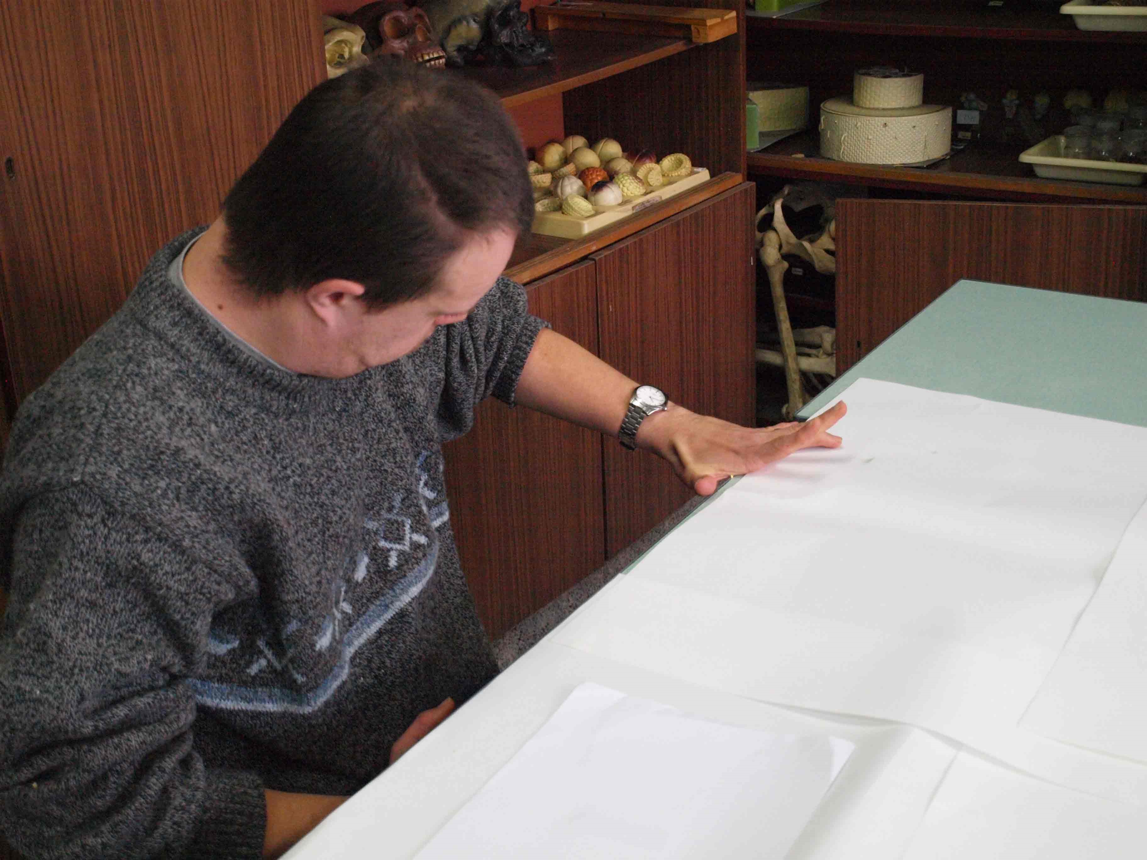 A student using their hand to measure the length of their desk.