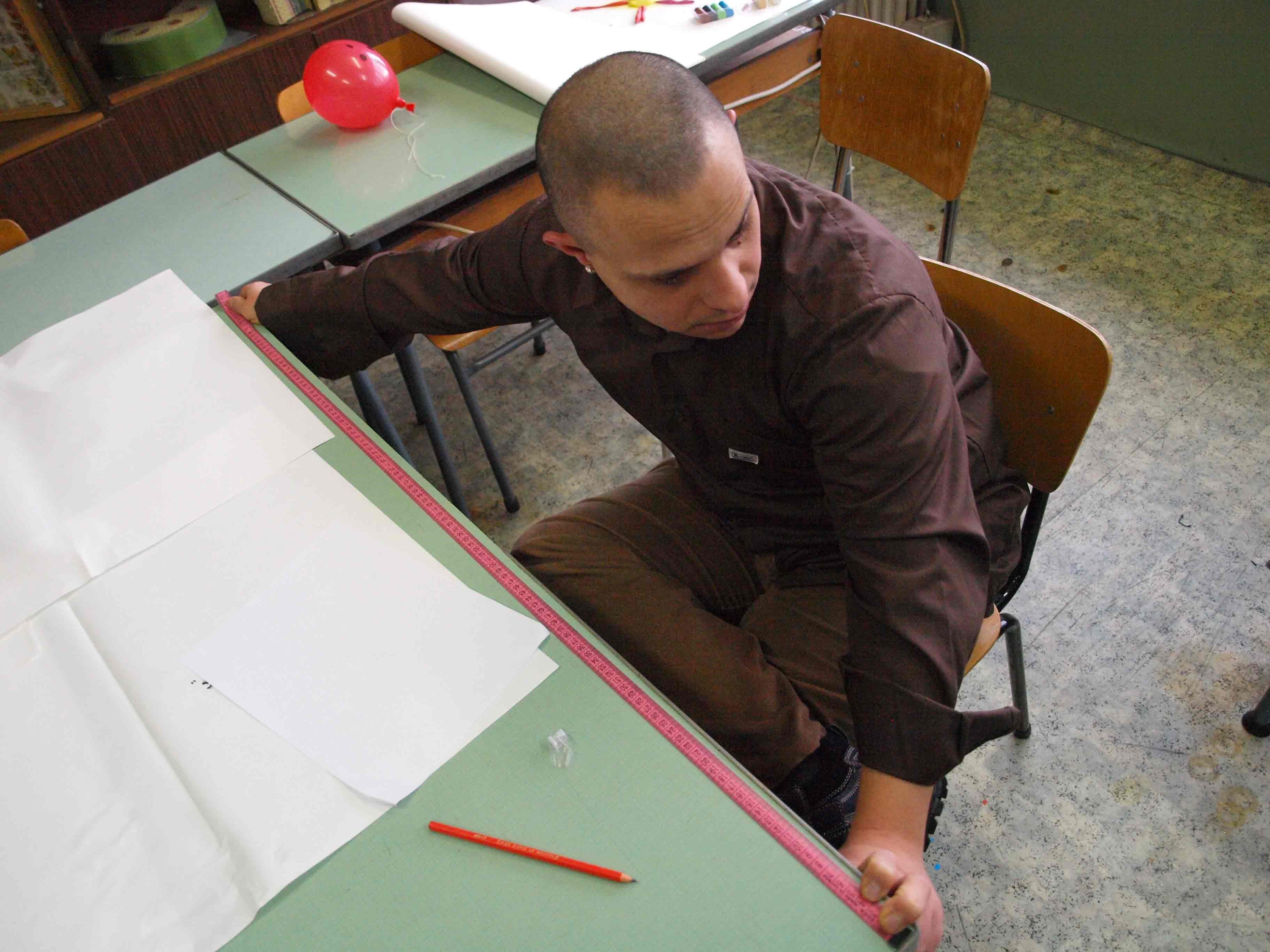 A student using a measuring tape to measure the length of their desk.