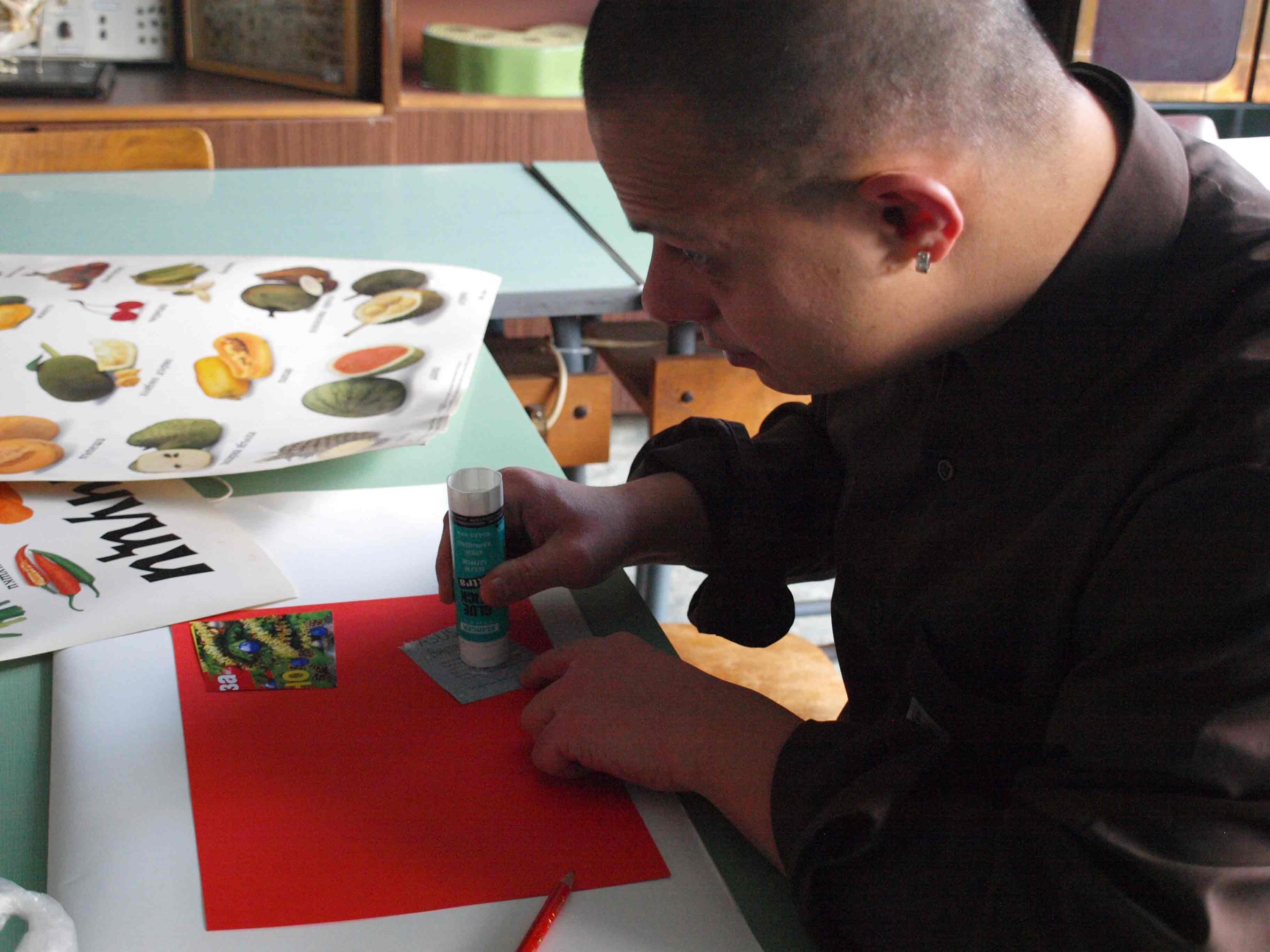 A student gluing a cutout of a paper to another paper.