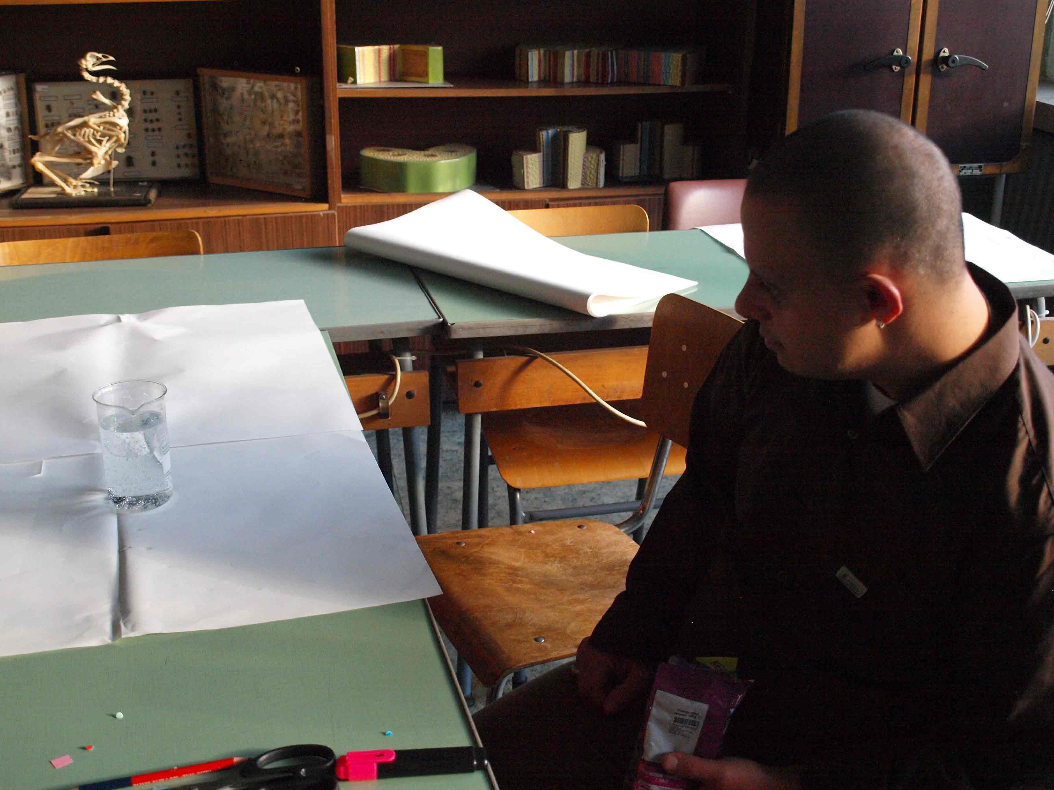 A student watching a glass filled with a soft drink.