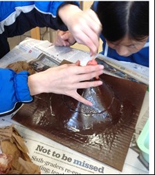 A student with hands on a model volcano.