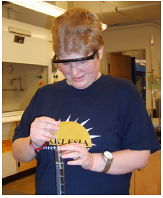 A student using a pipet in a graduated cylinder.
