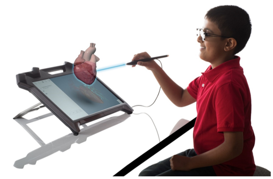 A boy is wearing the eyewear and holding the stylus, interacting with a 3D projected image of a heart from the display.